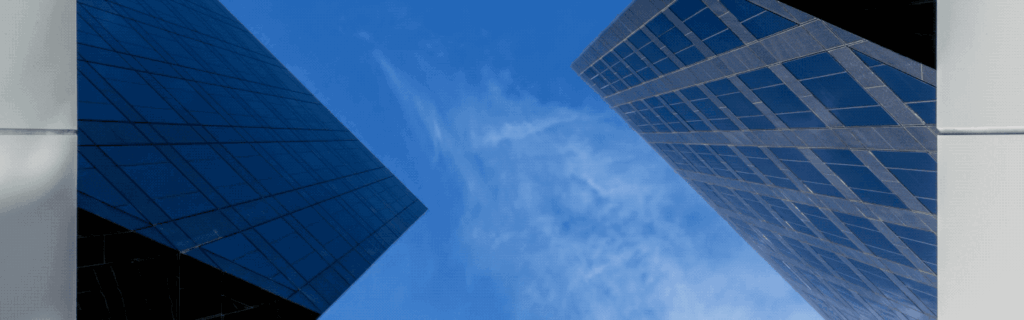 View of clouds passing by looking straight up at the towers of Newport Gateway in Irvine, CA.