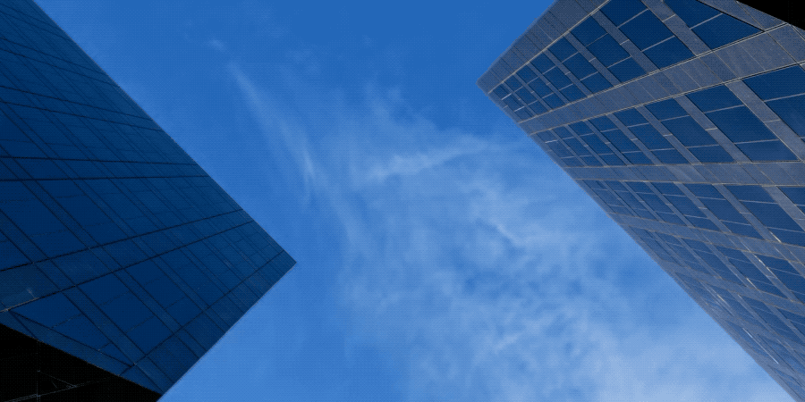 View of clouds passing by looking straight up at the towers of Newport Gateway in Irvine, CA.